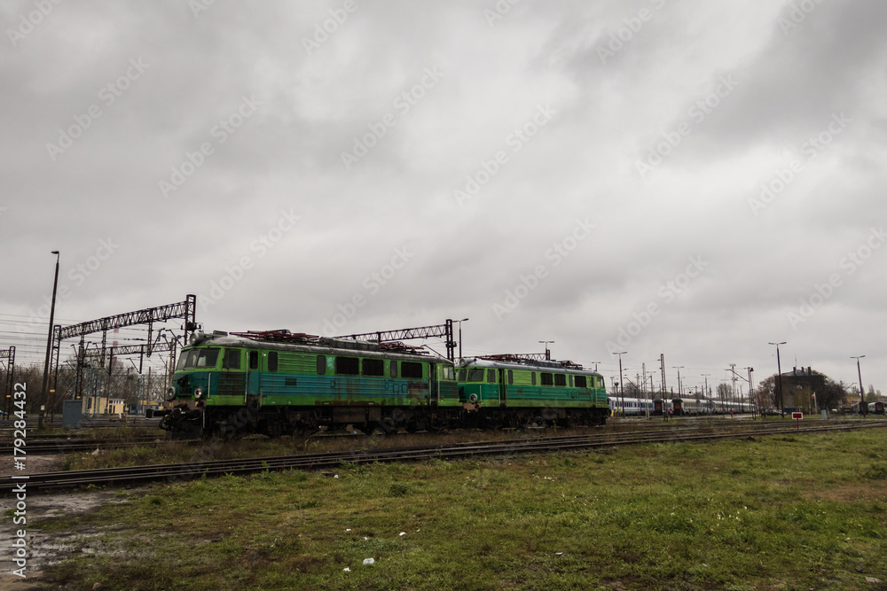 Old green trains on the tracks grown with grass under the cloudy day
