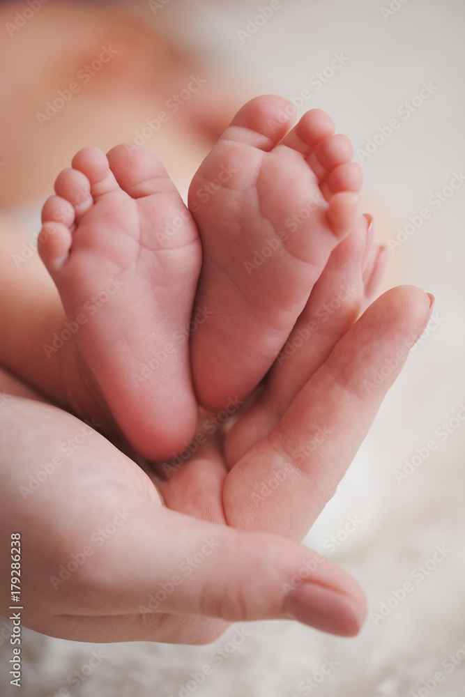 mother holds little foot of newborn baby - obrazy, fototapety, plakaty 