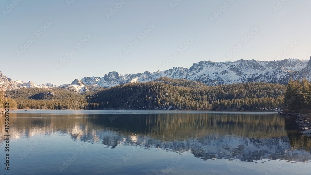 snowy hills reflection in the forest lake