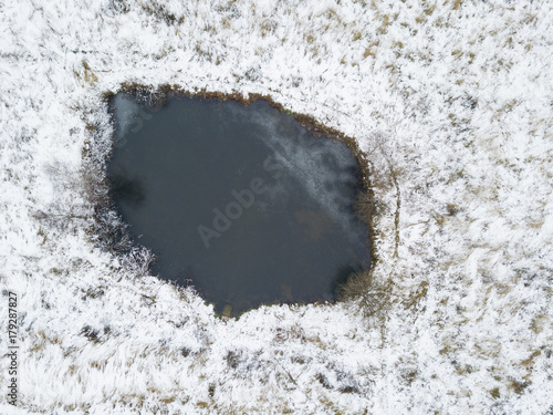 Small pond. Snow on the shore. View from above photo