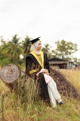 Wallpaper Mural Portrait of attractive young woman in the middle of field, sitting on died tree, with convocation or graduation dress. Torontodigital.ca