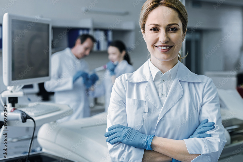 Professional science. Confident nice female scientist standing cross handed and smiling while looking at you