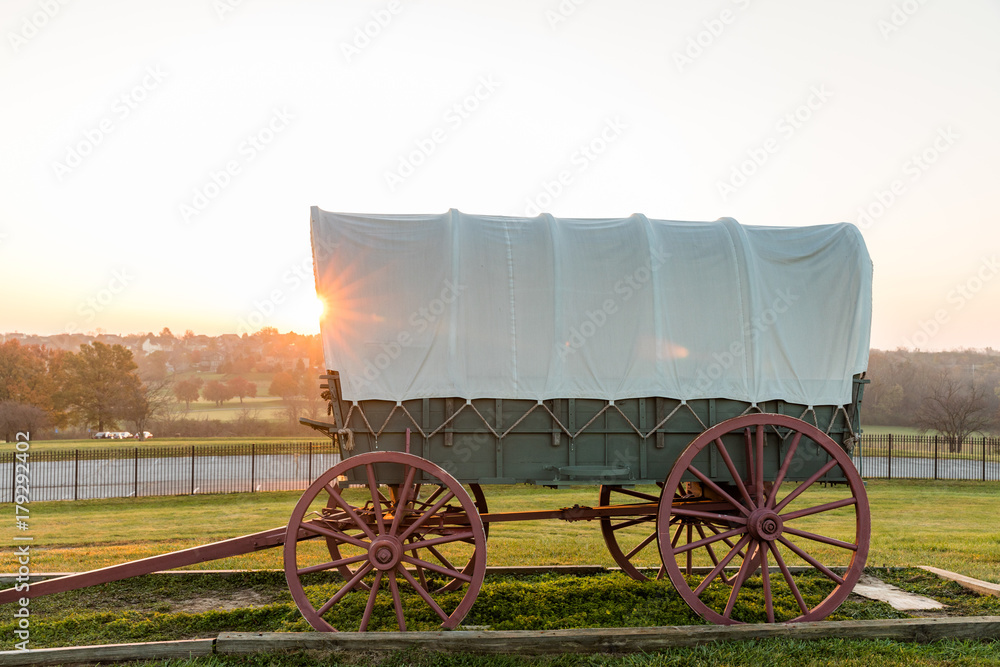 covered wagon in park at sunrise