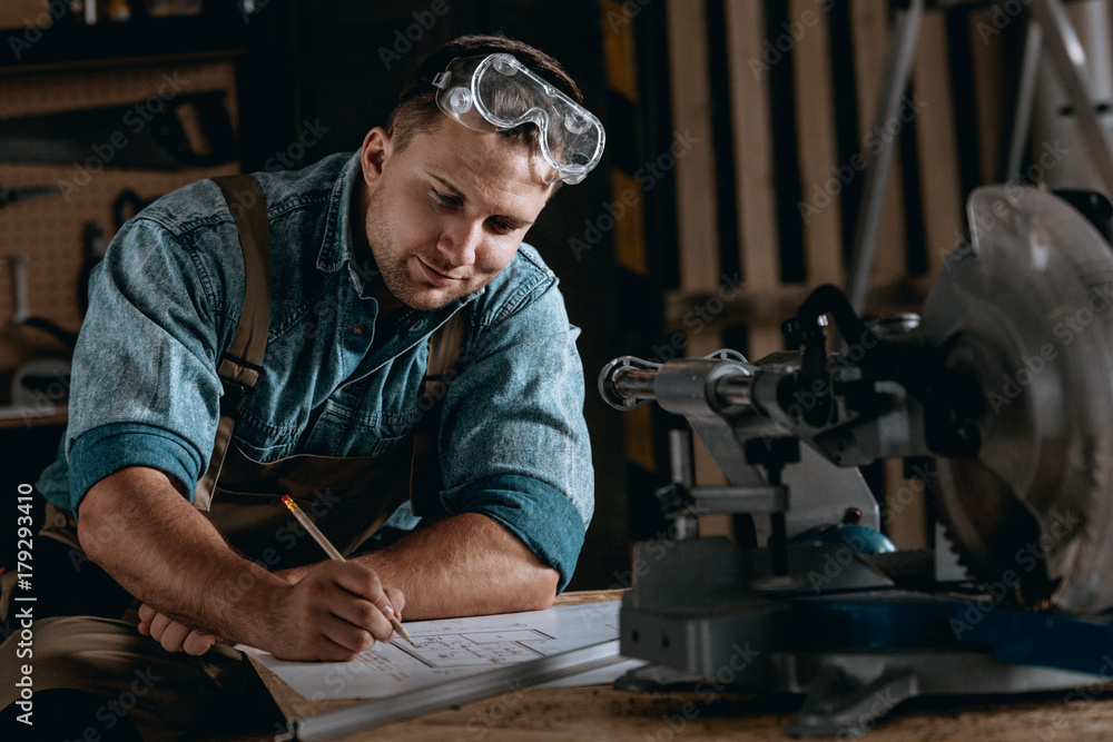Skilled woodworker drawing new project Skilled woodworker drawing new project