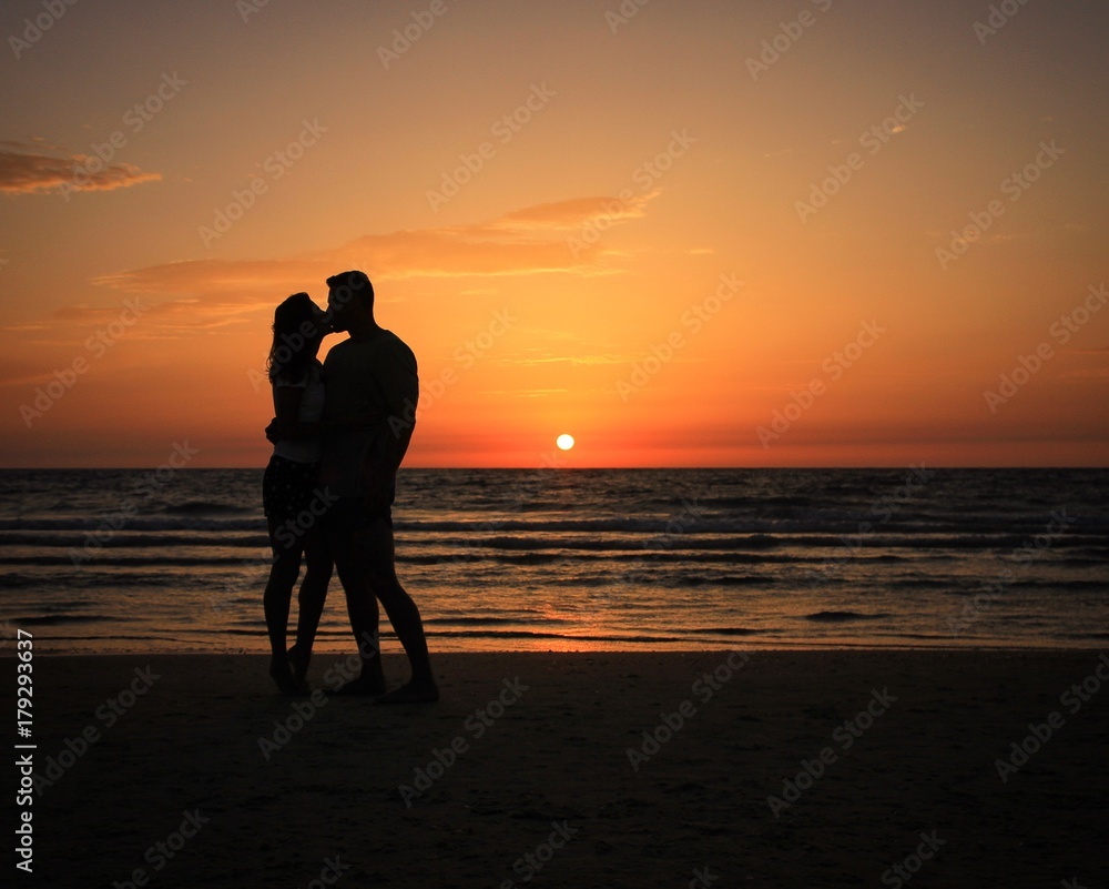 Two in love people on the beach during sunset