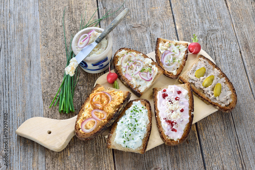 Brotaufstriche auf rustikalem Bauernbrot: Griebenschmalz, Obatzda, Schnittlauchquark, Preiselbeer-Meerrettich-Quark und Landleberwurst -  Hearty Bavarian snack: various spreads on dark farmhouse bread photo