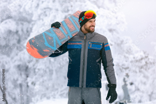 Snowboarder holding board on terrain