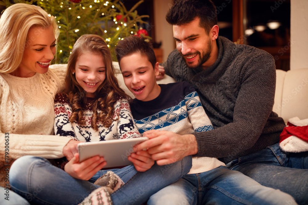 Family gathered around a Christmas tree and using tablet. Family gathered around a Christmas tree and using tablet.