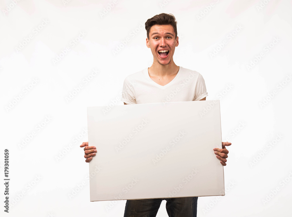 Young cheerful man portrait of a confident businessman showing presentation, pointing paper placard gray background. Ideal for banners, registration forms, presentation, landings, presenting concept. Young cheerful man portrait of a confident businessman showing presentation, pointing paper placard gray background. Ideal for banners, registration forms, presentation, landings, presenting concept.