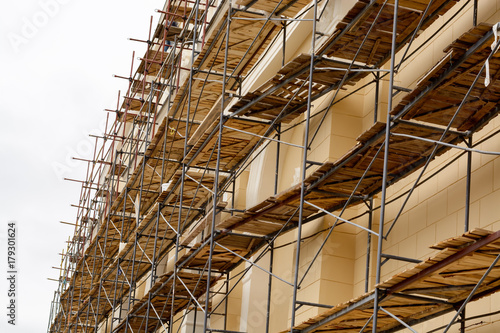 Metal scaffolding with wooden decking built around a historic building for restoration work and renovation of the facade. Construction works. Building construction.