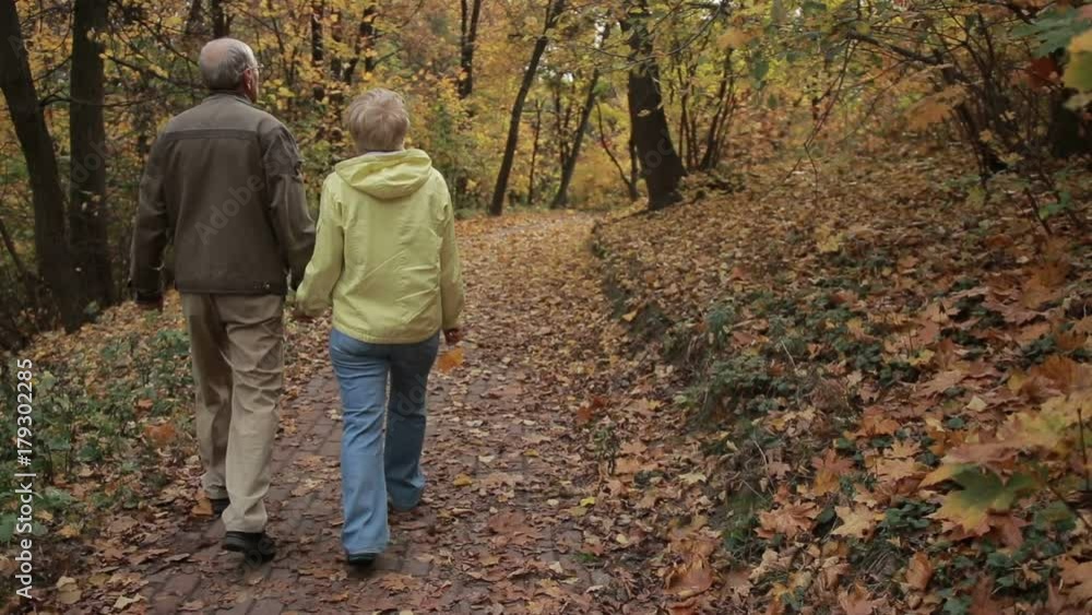 Senior couple enjoys romantic walk in autumn park Senior couple enjoys romantic walk in autumn park