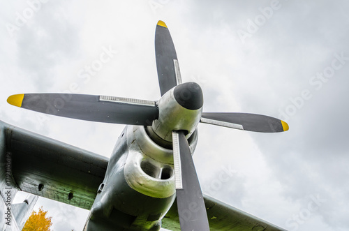 Close up of airplane turboprop engine with propeller, parts of aircraft fuselage, wings and tail on a cloudy sky background
