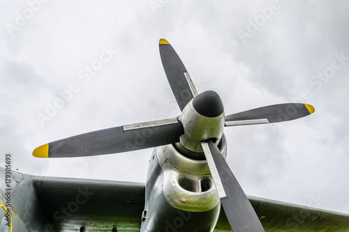 Close up of airplane turboprop engine with propeller, parts of aircraft fuselage, wings and tail on a cloudy sky background