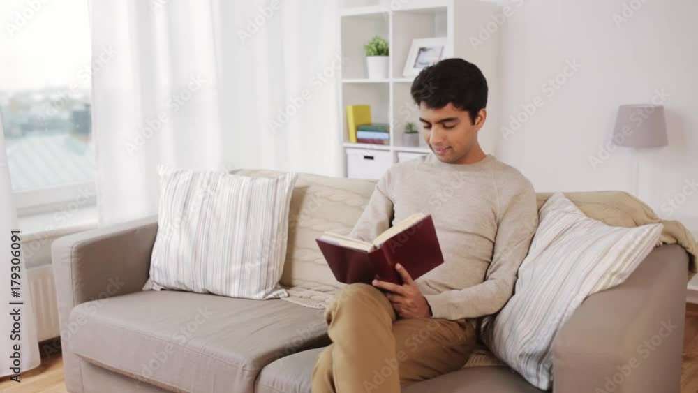 happy man sitting on sofa and reading book at home happy man sitting on sofa and reading book at home