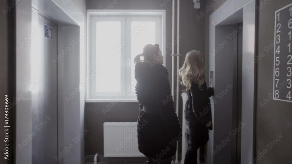 Two girls call the elevator and wait Two girls call the elevator and wait