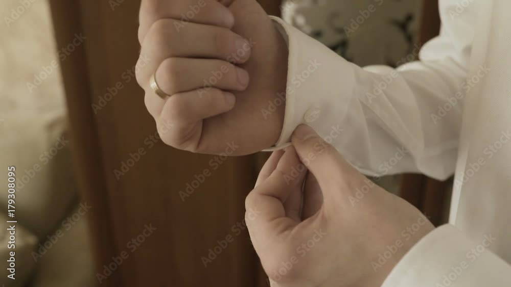 The man fastens the shirt sleeve