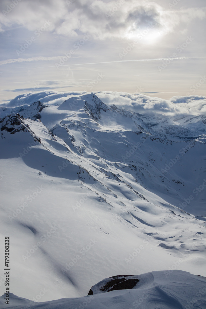 The mountain peaks covered with snow above clouds, Zell am See, Austria The mountain peaks covered with snow above clouds, Zell am See, Austria