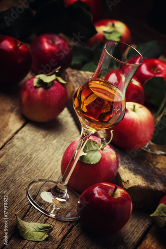 Strong golden alcoholic drink from apples, vintage wooden background, selective focus