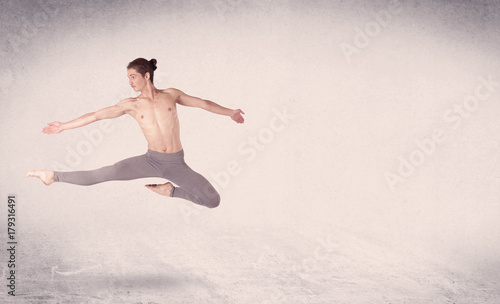 Modern ballet dancer performing art jump with empty background