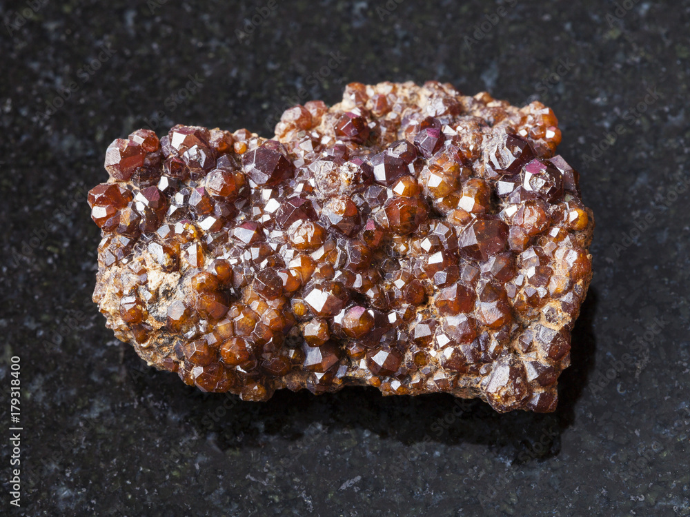 raw Andradite garnet crystals on stone on dark