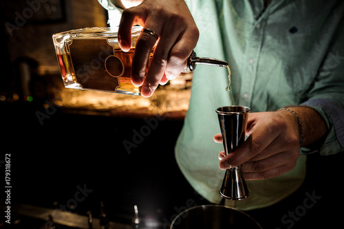 Barmans hands pouring a syrup for making a cocktail