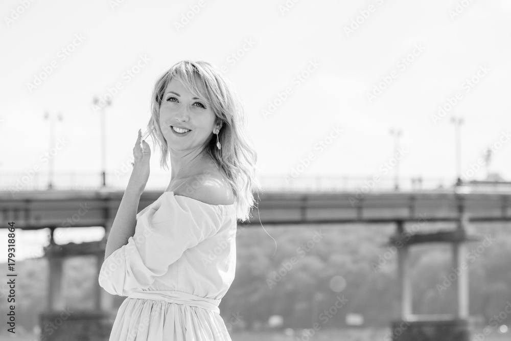 Beautiful and natural portrait of female by the river port. Happy woman plus size standing at the seaside and looking away. Concept of harmony on weekend at city