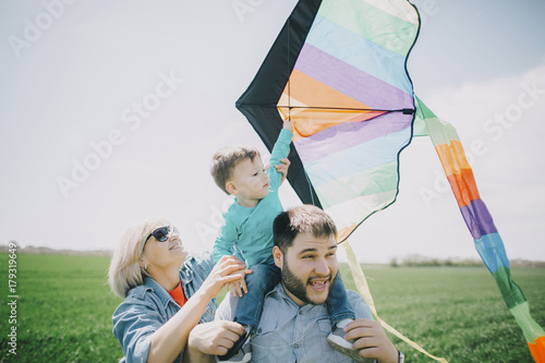 Caucasian boy flying kite with father and grandmother photo