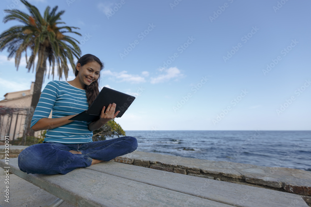 An Asian woman is working with laptop on a beach