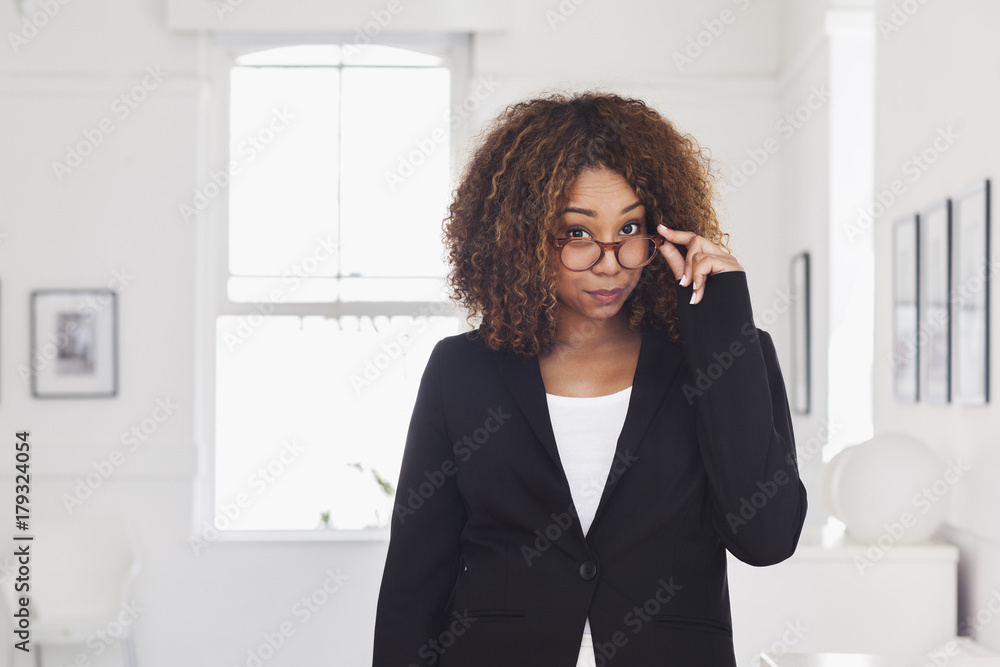 Mixed race woman peering over eyeglasses in gallery Mixed race woman peering over eyeglasses in gallery
