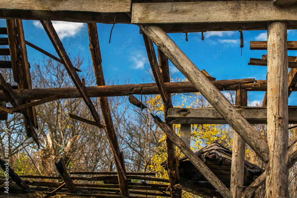 An old abandoned ruined wooden building. Building debris. The wooden poles. A framework