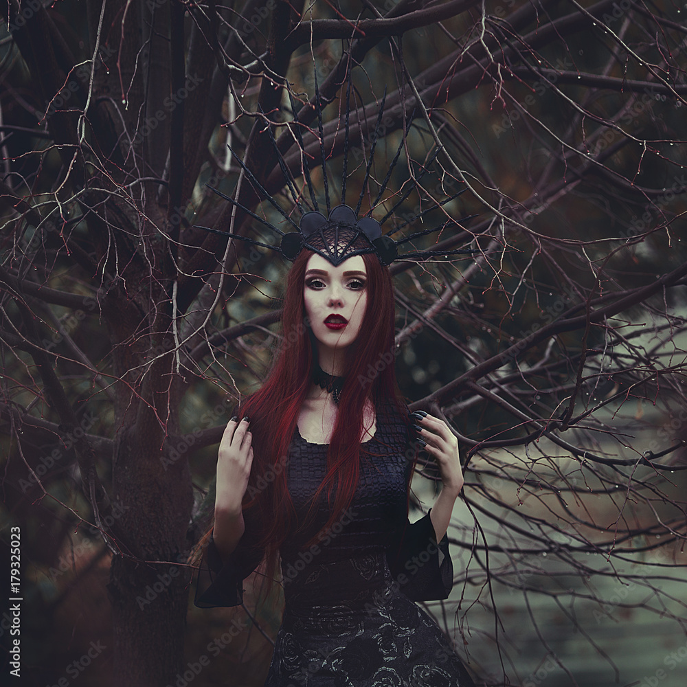 A beautiful woman with pale skin and long red hair in a black dress and ...