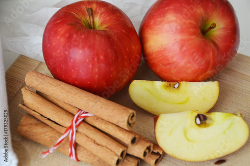 Red apples and cinnamon sticks on wooden background