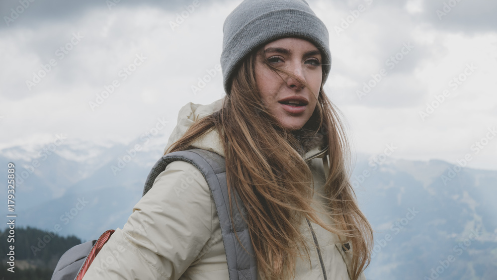 Hipster young girl with backpack hiking in mountains. Tourist traveler walking on top of the mountain Hipster young girl with backpack hiking in mountains. Tourist traveler walking on top of the mountain