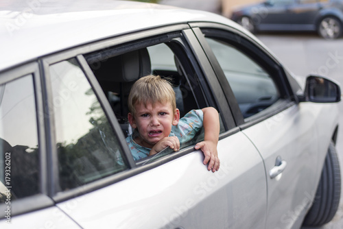 child separated from one parent leaving in a car, sad and crying