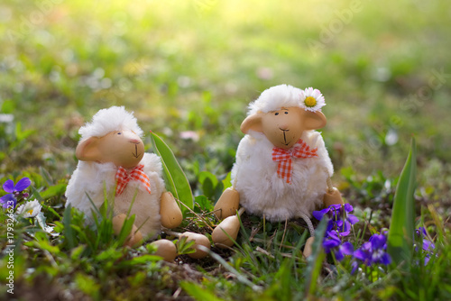 Easter lambs sitting in the grass, sheep toy looking for Easter.