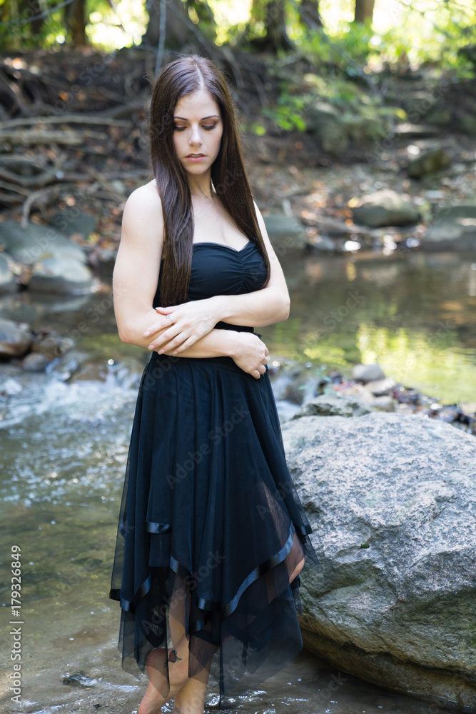 Portrait with elegance and confidence of a beautiful young woman with a background of a stream and forest Portrait with elegance and confidence of a beautiful young woman with a background of a stream and forest