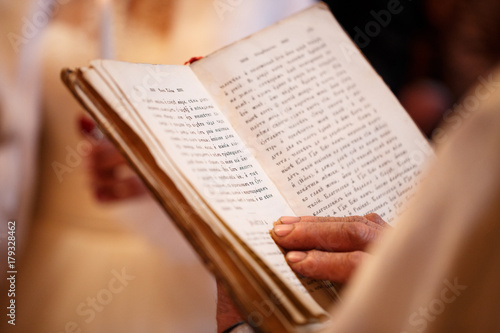 priest holding a large book of the Bible