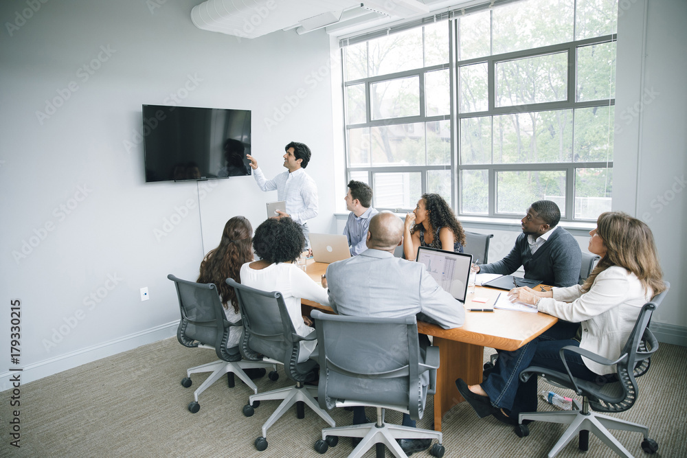 Businessman talking near visual screen in meeting Businessman talking near visual screen in meeting
