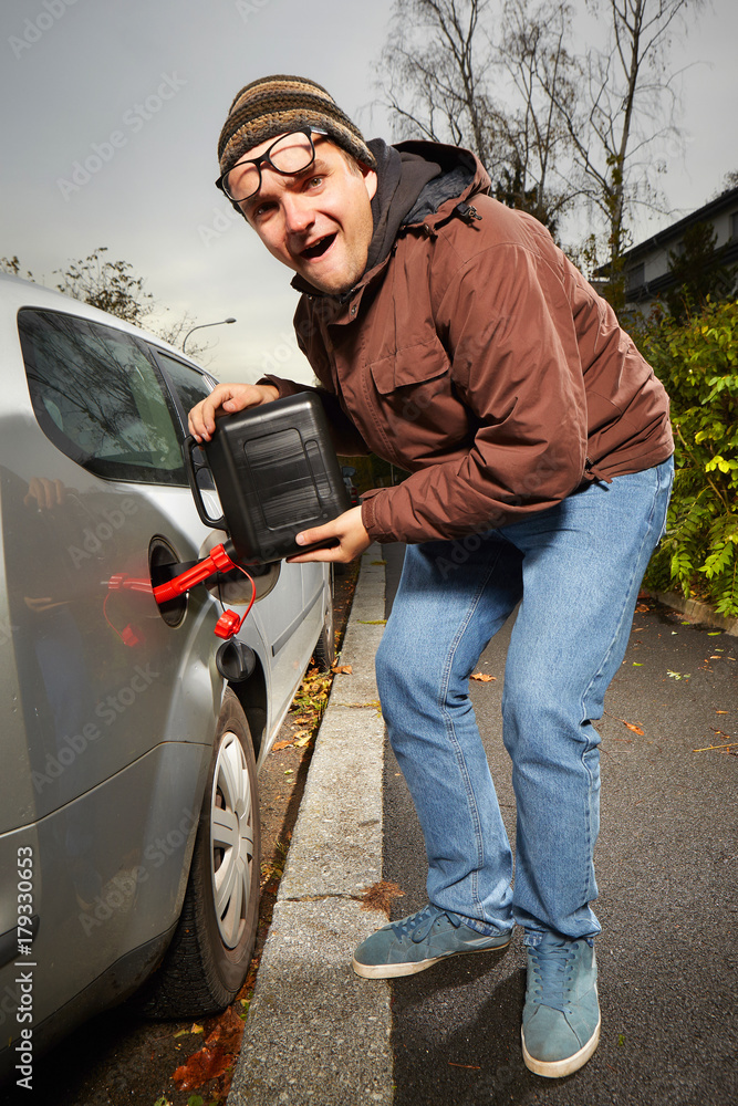 Smiling man with plastic canister filling car tank on street