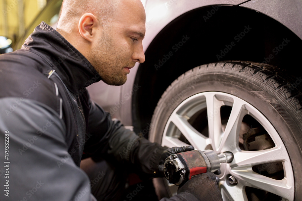 auto mechanic with screwdriver changing car tire auto mechanic with screwdriver changing car tire