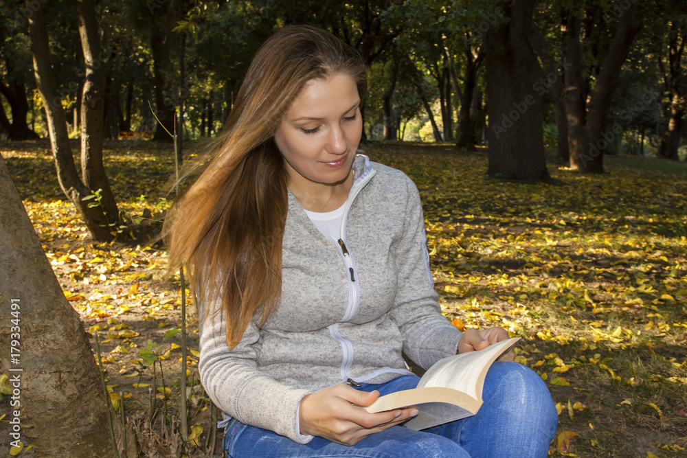 Young blonde woman reading a book at the park and wind in hair Young blonde woman reading a book at the park and wind in hair