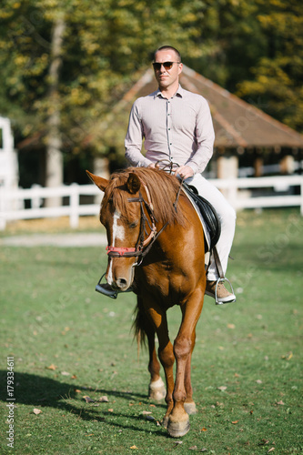 Elegant casually dressed man riding a horse