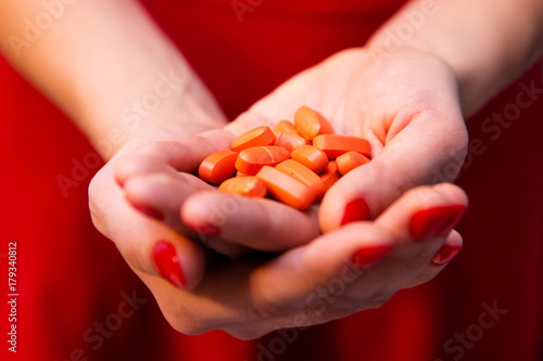 Woman's hands with red manicure holding vitamin pills