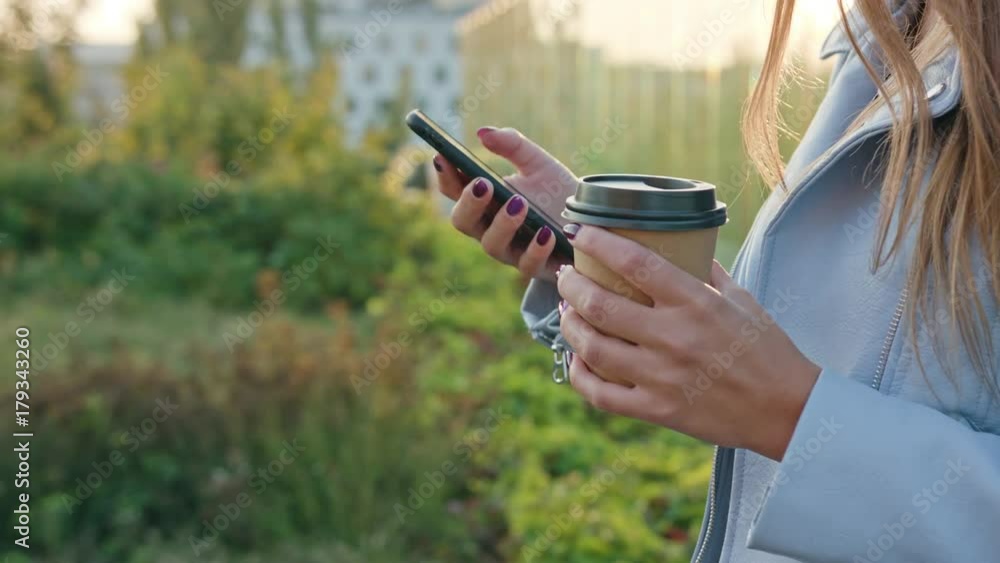 A young lady walking and using a phone outdoors. Close-up Dolly shot. Soft focus. A young lady walking and using a phone outdoors. Close-up Dolly shot. Soft focus.