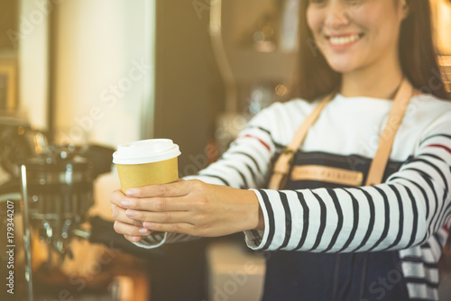 Happy barista serving a cup of coffee to customer with beautiful smile