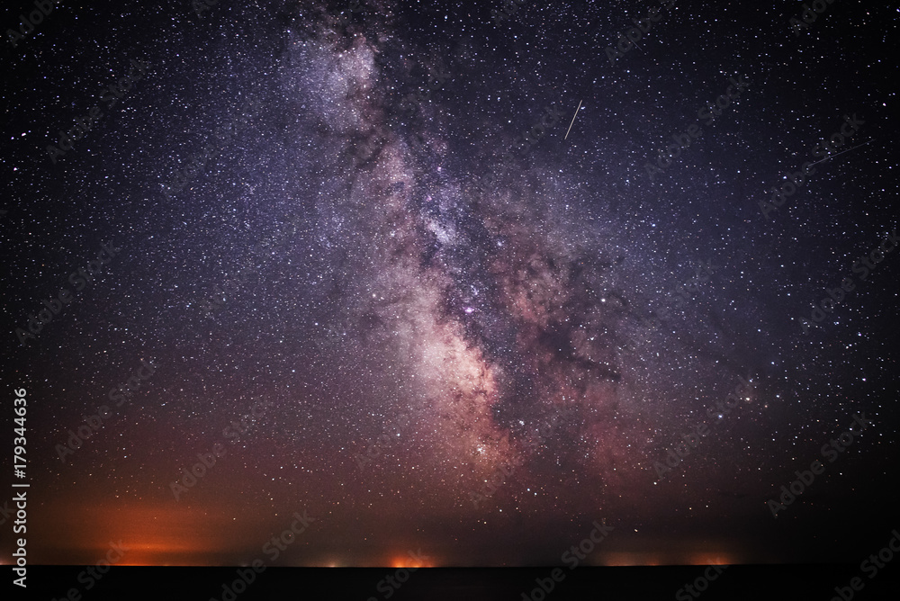 Fototapeta premium Background of bright and night-starry sky with the Milky Way upon on it and light over the water