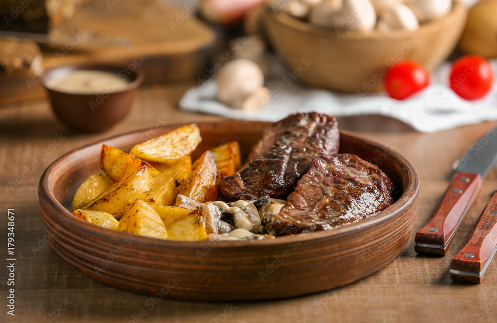 Plate with steak Diane and vegetable garnish on wooden table Plate with steak Diane and vegetable garnish on wooden table