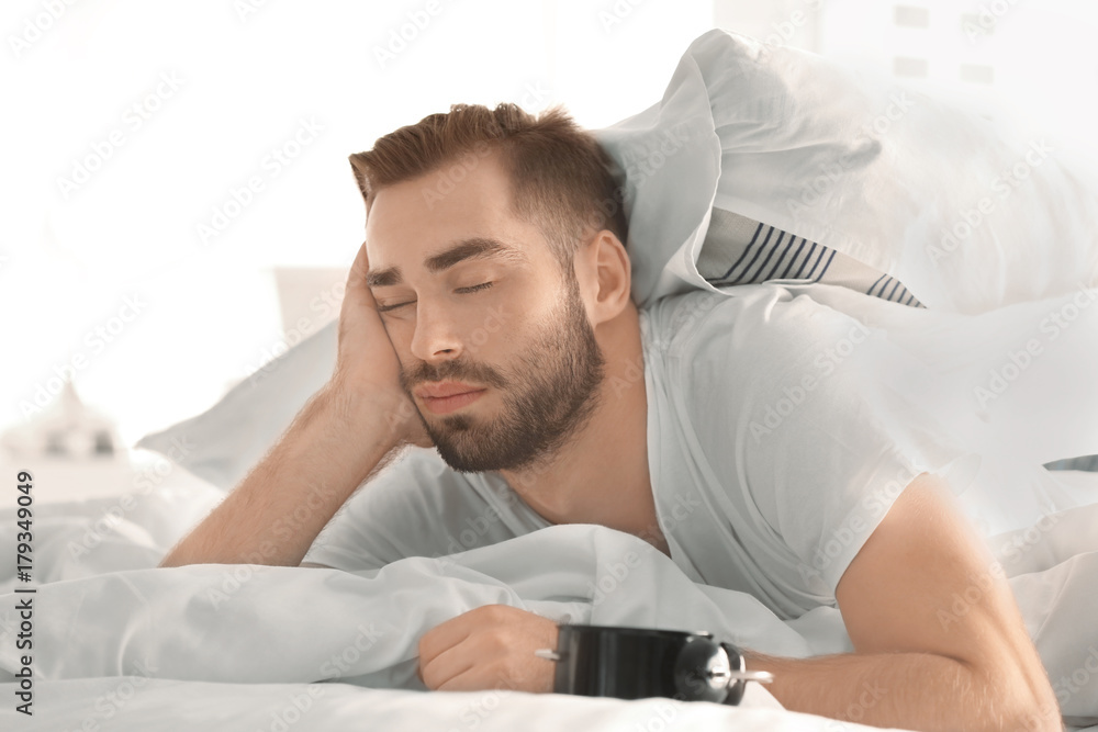 Young sleepy man lying in bed at home Young sleepy man lying in bed at home