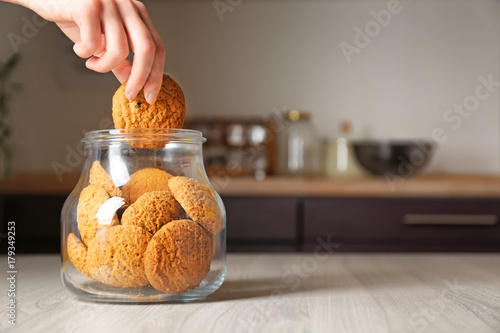 Photo Woman taking oatmeal cookie from glass jar