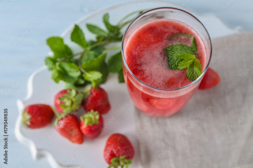 Glass with delicious strawberry smoothie on light background Glass with delicious strawberry smoothie on light background